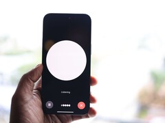 Una mano que sostiene un smartphone con una interfaz de asistente de voz en la pantalla