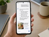 Una mano que sostiene un smartphone en el que se muestra una respuesta generada por IA, con un anuncio patrocinado debajo.