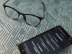 Un smartphone con la aplicación ChatGPT abierta junto a unas gafas sobre una superficie estampada