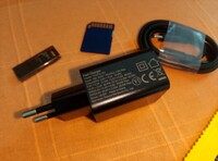 El cargador y el cable, una tarjeta SD y un pen drive USB a escala (Fuente de la imagen: Sergey Tarasov - Notebookcheck)