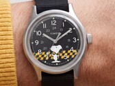 Primer plano de la esfera negra del Timex MK1, en la que aparece Snoopy sobre un fondo a cuadros amarillos y negros, con índices arábigos y agujas luminosas.