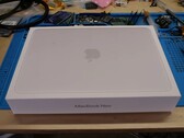 Caja de venta del MacBook Neo colocada en un banco de trabajo antes del desmontaje para la actualización de la SSD
