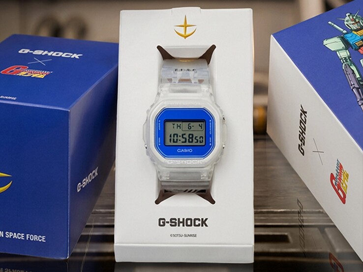 Casio G-Shock x Mobile Suit Gundam DW-5600 con caja y correa transparentes, bisel azul, marca E.F.S.F. y embalaje de coleccionista con ilustraciones de Gundam.