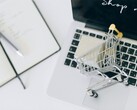 Carrito de la compra en miniatura sobre el teclado de un ordenador portátil, con el mensaje «Comprar ahora» en la pantalla