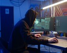 Hacker genérico en una estación de trabajo con dos monitores ejecutando un ataque a la cadena de suministro.