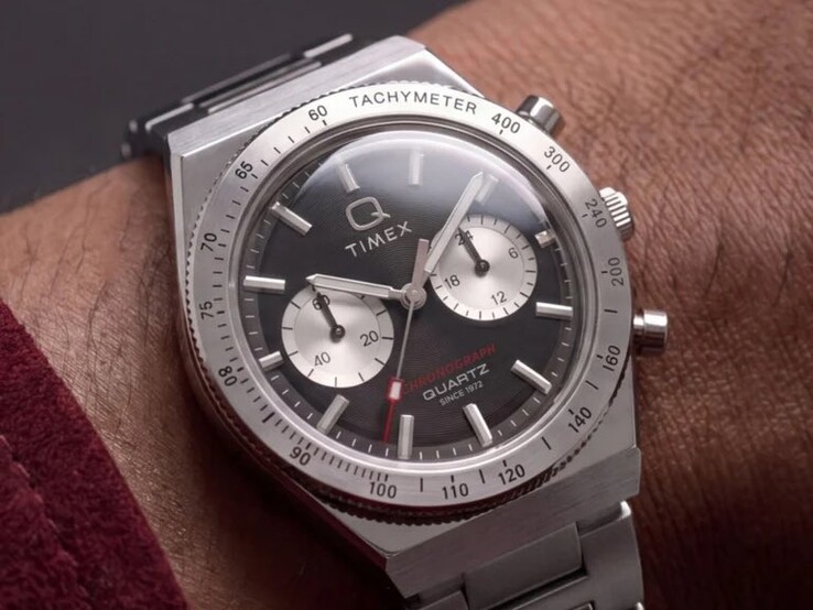 El cronógrafo Timex Q Timex Continental TW2Y93200 en la muñeca, con una esfera negra radial de estilo CD, dos subesferas plateadas, bisel taquimétrico, índices luminosos y un brazalete integrado de acero inoxidable.