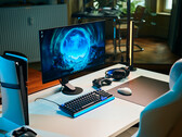 Una configuración de gaming minimalista en un estudio, con el monitor Sony Inzone M10S II sobre un escritorio blanco, junto a una consola PlayStation 5 Pro colocada en vertical, un teclado mecánico, un ratón inalámbrico y unos auriculares con una sutil iluminación azul.