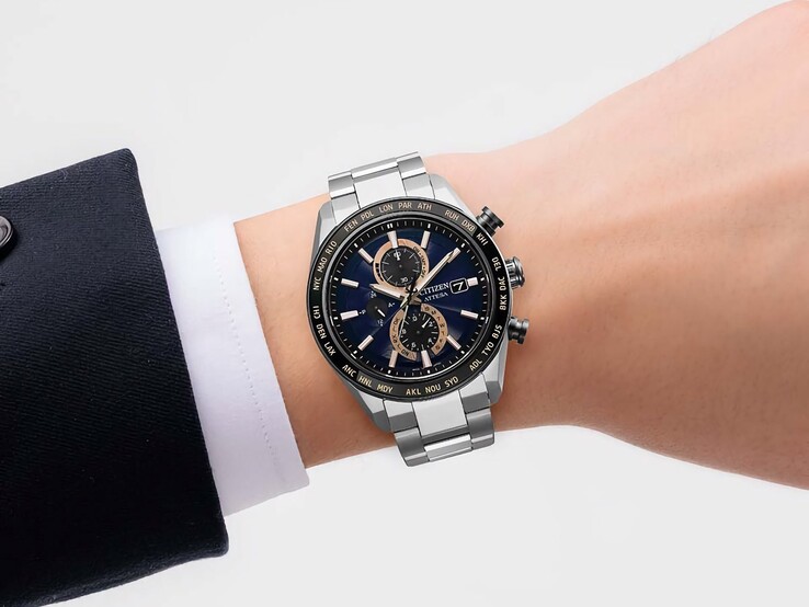 Cronógrafo Citizen Attesa AT8297-51L llevado en la muñeca, que muestra su esfera azul marino, detalles en oro rosa y bisel negro de hora mundial.