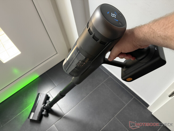 Roborock H60 Ultra limpiando el suelo, en la parte superior la pantalla rudimentaria