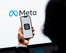 Una mano sostiene un smartphone frente a un gran logotipo de Meta