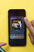 Un smartphone OnePlus en el que se muestra el widget del reproductor multimedia, y en el que un usuario pulsa el icono de salida de audio para acceder a los controles de compartición de audio por Bluetooth.