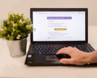 Un ordenador portátil sobre un escritorio en el que se ve una bandeja de entrada de correo electrónico abierta, con una planta en maceta junto a él.