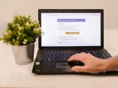 Un ordenador portátil sobre un escritorio en el que se ve una bandeja de entrada de correo electrónico abierta, con una planta en maceta junto a él.