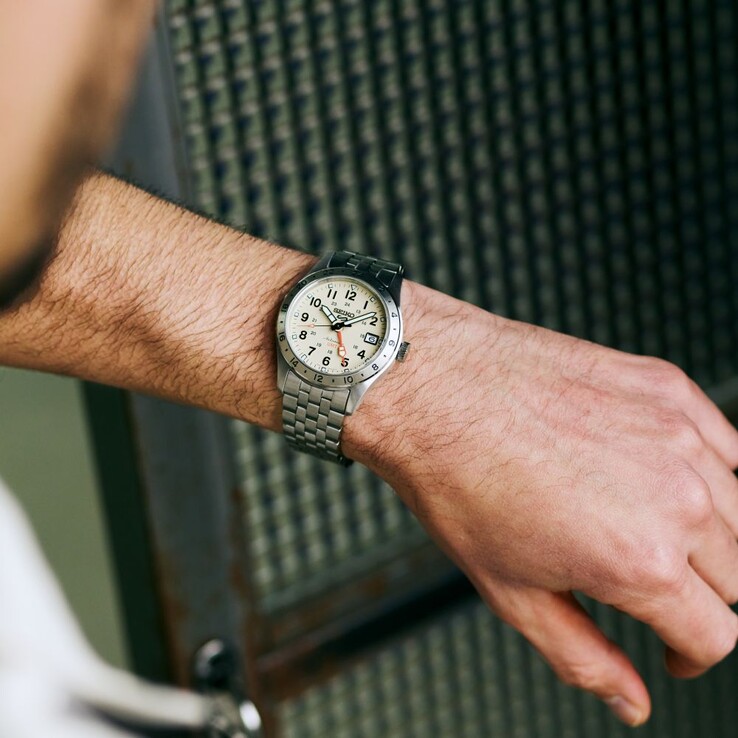 Vista frontal del Seiko 5 Sports Field GMT HDB002 con esfera color crema, manecilla GMT naranja, bisel fijo de 24 horas y brazalete de acero inoxidable.