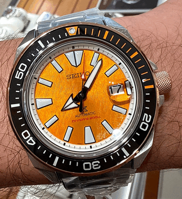 Primer plano del Seiko Prospex HBB005K1 en el que se aprecia su esfera de color ámbar con textura, los índices luminosos de gran tamaño, las agujas anchas, la ventana de fecha y el bisel de buceo negro con marcas naranjas.