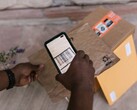 Una mano sostiene un teléfono inteligente sobre un paquete y escanea su código de barras.