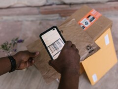 Una mano sostiene un teléfono inteligente sobre un paquete y escanea su código de barras.