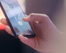Una mano sostiene un smartphone y lo desbloquea mediante el sensor de huellas dactilares de la pantalla de bloqueo.
