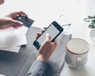 Persona que teclea en un smartphone mientras sostiene una tarjeta bancaria en la otra mano