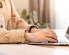 Unas manos tecleando en el teclado de un ordenador portátil abierto sobre un escritorio bien iluminado