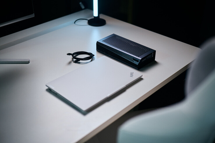 Un portátil ThinkPad blanco cerrado, situado junto a la compacta eGPU Aorus RTX 5060 Ti AI Box y un cable Thunderbolt en espiral sobre un escritorio.