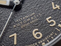 Primer plano de la esfera negra texturizada del Timex Expedition Field Post Titanium, con números arábigos, agujas e índices luminosos y ventana de fecha.