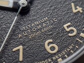 Primer plano de la esfera negra texturizada del Timex Expedition Field Post Titanium, con números arábigos, agujas e índices luminosos y ventana de fecha.