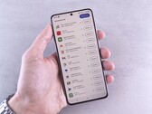 Una mano sostiene un smartphone en cuya pantalla se muestra una lista de actualizaciones.
