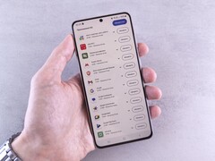 Una mano sostiene un smartphone en cuya pantalla se muestra una lista de actualizaciones.