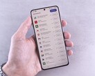 Una mano sostiene un smartphone en cuya pantalla se muestra una lista de actualizaciones.