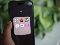 Mano sosteniendo un smartphone con una carpeta llena de aplicaciones de IA en la pantalla