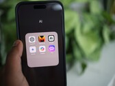 Mano sosteniendo un smartphone con una carpeta llena de aplicaciones de IA en la pantalla