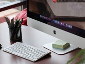 Un iMac sobre un escritorio con el dock de macOS visible en la pantalla y un teclado de Apple delante