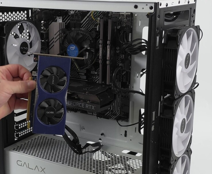Una mano sostiene una tarjeta gráfica Intel Arc A380 junto a un PC con una Nvidia GeForce RTX 3060, preparada para una configuración de doble GPU con Lossless Scaling (Fuente de la imagen: ETA PRIME vía YouTube)
