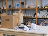 Una caja de cartón y bolsas de papel sobre una mesa de madera en una oficina con estanterías