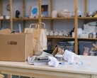 Una caja de cartón y bolsas de papel sobre una mesa de madera en una oficina con estanterías