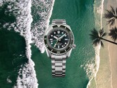 Reloj de buceo Seiko Prospex HBC001 con esfera y bisel verdes sobre un fondo aéreo de playa y océano.