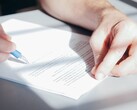 Una mano firma un documento con un bolígrafo azul.