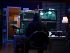 Figura encapuchada en un montaje multipantalla ejecutando un ciberataque.