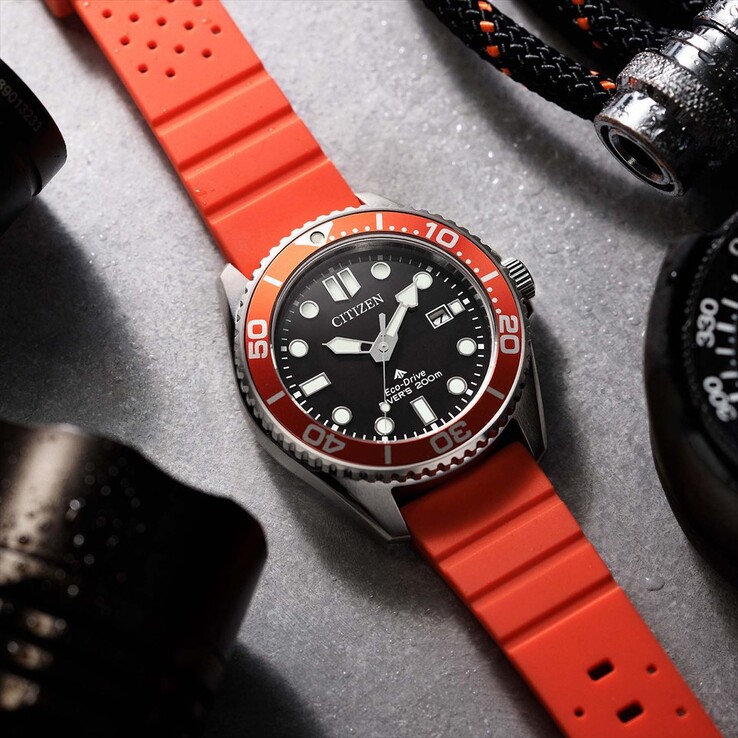 Reloj de buceo Citizen Promaster Marine BN0268-01E con esfera negra, bisel naranja y correa naranja, fotografiado sobre una superficie texturizada.