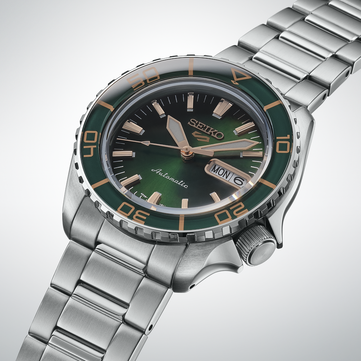 Primer plano del Seiko 5 Sports SKX HDB005, que destaca su esfera verde oscuro, sus agujas e índices aplicados de color oro rosa y su bisel verde a juego con marcas de color dorado.