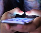 Dos manos sostienen un smartphone con la pantalla iluminada en la penumbra