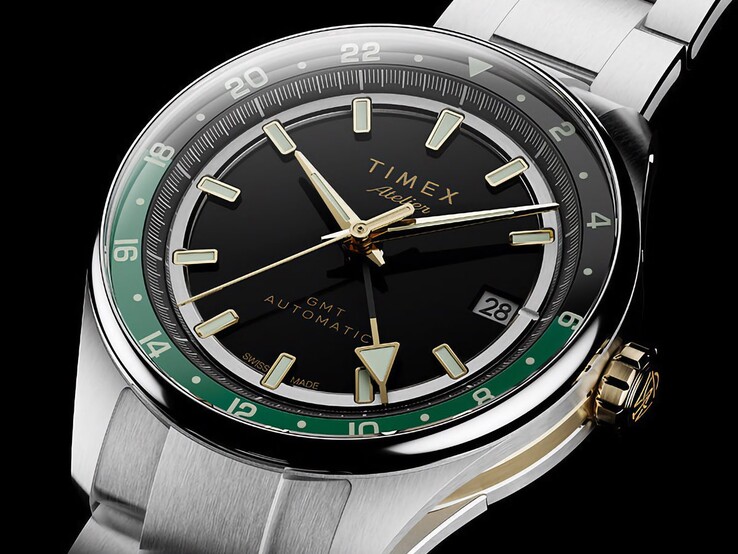 Vista en ángulo del Timex Atelier GMT Première M1a, que muestra su esfera negra, el anillo GMT verde, la corona en tono dorado y el brazalete de acero inoxidable.