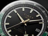 Primer plano de la esfera negra del Timex Atelier GMT Première M1a, con manecillas en tono dorado, índices horarios luminiscentes, ventana de fecha y anillo GMT de 24 horas en negro y verde.