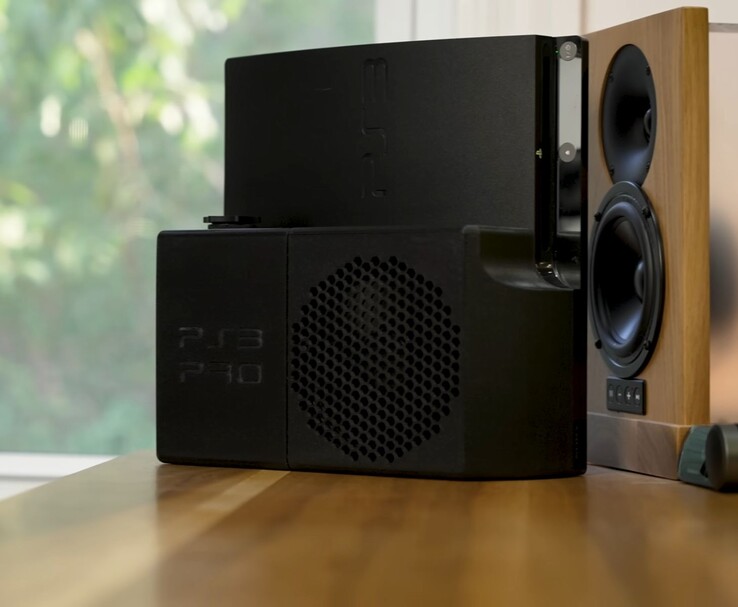 PlayStation 3 refrigerada por agua con una carcasa trasera negra "PS3 Pro" impresa en 3D junto a un altavoz de madera. (Fuente de la imagen: Zac Builds vía YouTube)