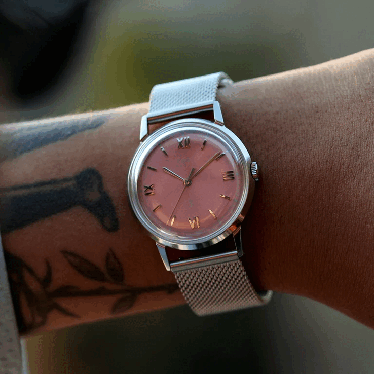 Persona que lleva el reloj Timex x Todd Snyder Marlin Mesh con esfera color salmón con efecto rayos de sol y brazalete de malla.