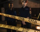 Dos agentes de policía de pie por la noche detrás de una cinta amarilla que dice Stop
