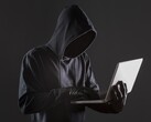 Un hacker encapuchado manejando un ordenador portátil sobre un fondo oscuro.