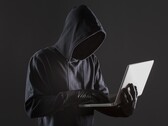 Un hacker encapuchado manejando un ordenador portátil sobre un fondo oscuro.