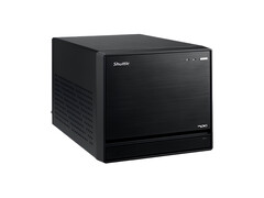 La imagen muestra una vista frontal del Shuttle XPC Mini PC, que parece un cubo negro con un diseño minimalista. 